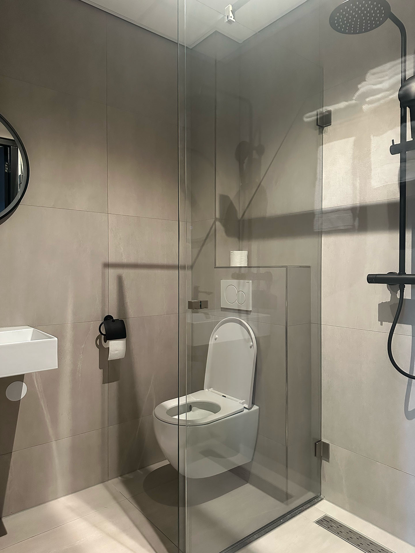 Moderne badkamer met glazen douchecabine, toilet, bidetkraan en regendouchekop