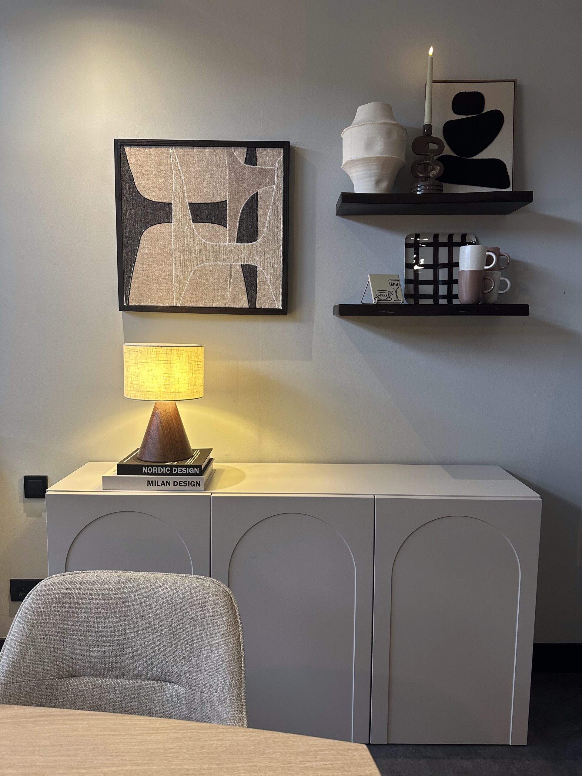 Interieurfoto van een kast met decoratie: lamp, kunstwerken en mokken op planken